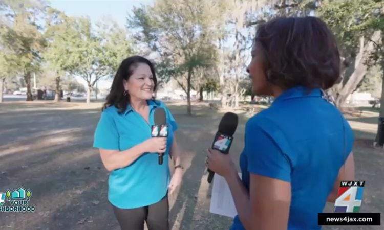 Woman holding microphone is interviewed in an outdoor setting